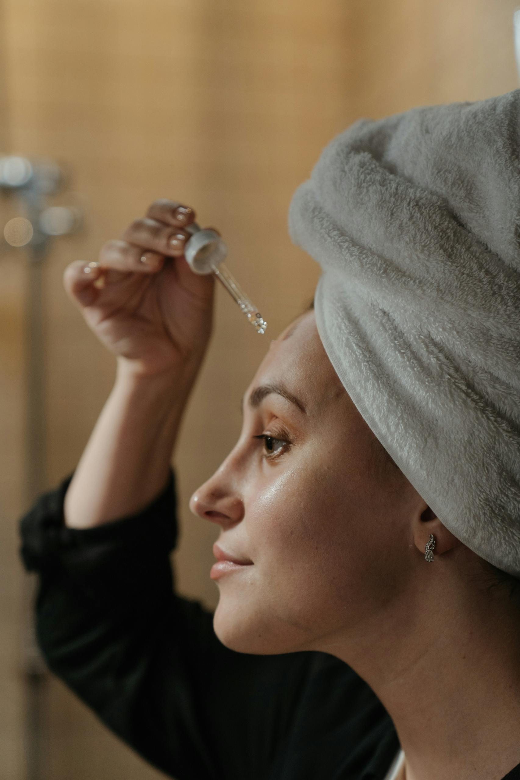 Close-up side view of a woman applying skincare serum with a dropper